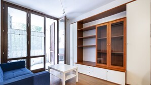 A room with a sofa, a table, and a large wooden cabinet with glass doors. - Berni - One Bedroom Apartment, Sleeps 2 (Florence)