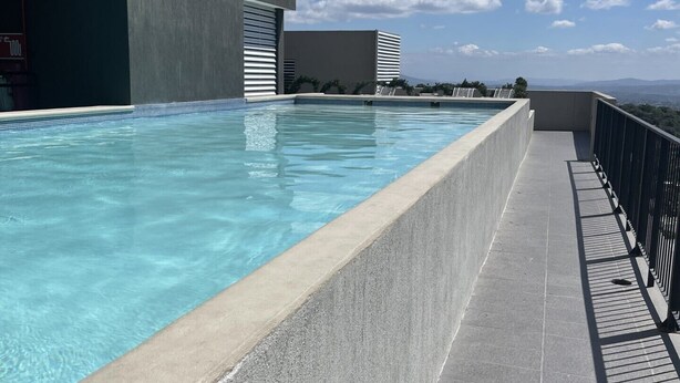 Una piscina a sfioro sul tetto con vista chiara sulla città e montagne sullo sfondo.