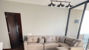 Un soggiorno moderno con un divano beige a forma di L, cuscini decorati e un pavimento in legno.