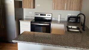 Una cucina moderna con frigorifero in acciaio inox, forno integrato, microonde e piano di lavoro in granito.