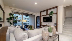 Uma sala de estar moderna com um sofá, uma mesa de centro e uma TV fixada na parede.