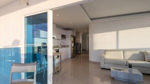 Eine moderne Wohnung mit einer Glastür zum Balkon, einer Küche mit Edelstahlgeräten, einem weißen Sofa und einem Marmortisch.