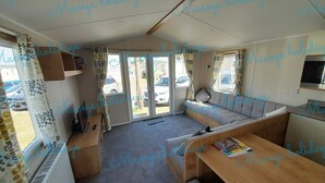 A cozy RV interior with a sofa, dining table, and a small kitchen area. - Pet Friendly Caravan in Walton on the Naze (Walton on the Naze)