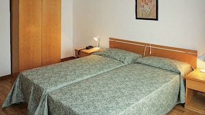 A single bed with a wooden headboard, a bedside table with a lamp, and a telephone. - Life Hotels Des Alpes (Folgaria)