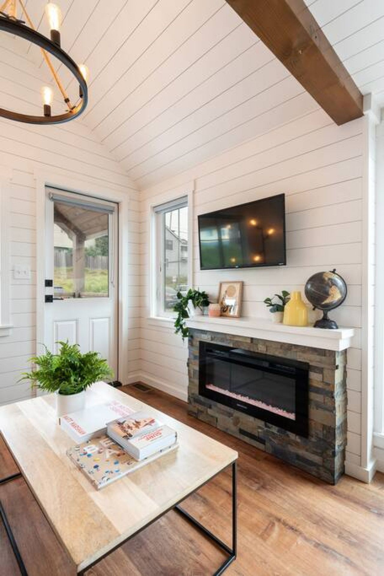 A room with a fireplace, a television mounted above it, and a door leading outside.