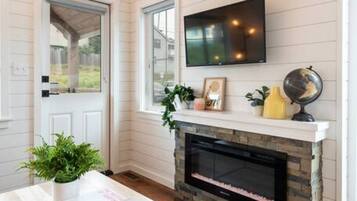 A room with a fireplace, a television mounted above it, and a door leading outside.