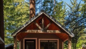 A cabin with a wooden exterior, a porch with a railing, and a window.