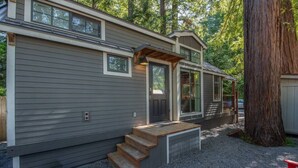 A two-story cabin with a front porch, a covered entryway, and a small outdoor seating area.