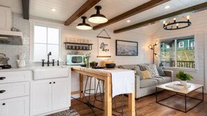 A cozy kitchen with white cabinets, a wooden island, and pendant lighting.