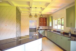 A modern kitchen with a central island, green cabinets, and pendant lighting. - Mount Pleasant - Luxurious 4-bed Villa (Harare)