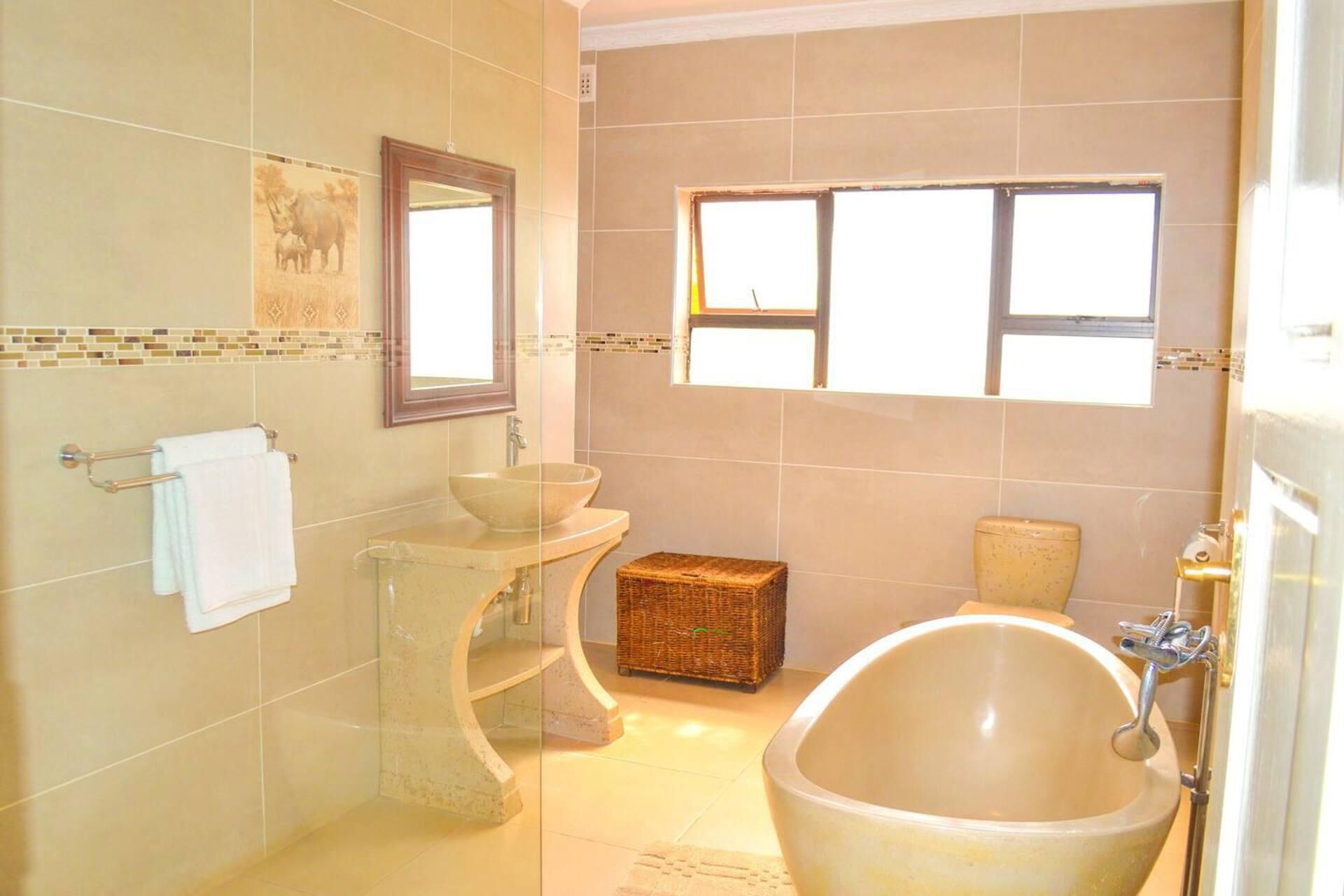 A bathroom with a freestanding bathtub, a sink with a bowl, a small wicker basket, and a towel rack.