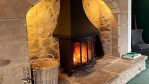 A stone fireplace with a black hood and a fire burning inside. - Exceptional Unique 5 Bedroom Manor House (Skipton)