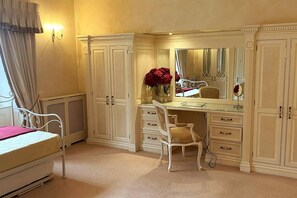 A bedroom with a bed, a vanity with a mirror, and a chair.