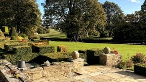 A landscaped garden with stone pathways, neatly trimmed hedges, and spherical stone ornaments. - Exceptional Unique 5 Bedroom Manor House (Skipton)