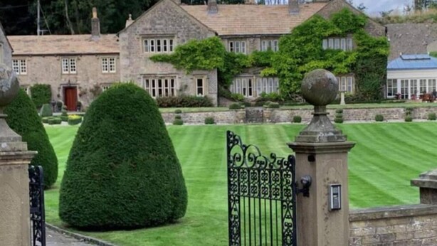 A stone building with a symmetrical facade, a well-manicured lawn, and a gated entrance. - Exceptional Unique 5 Bedroom Manor House (Skipton)