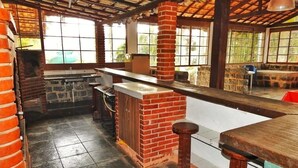 A rustic bar area with brick accents, a tiled floor, and a high ceiling with exposed beams.