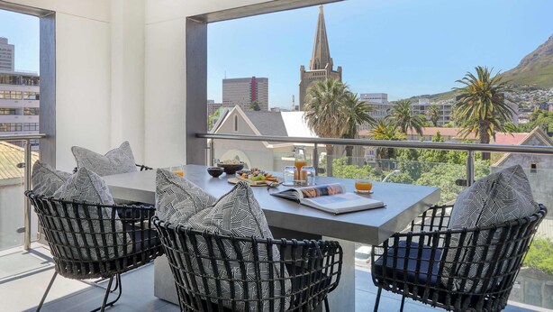 Ein Balkon mit Esstisch, Stühlen und Blick auf einen Kirchturm und Gebäude.
