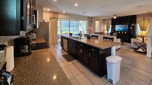 A modern kitchen with dark cabinetry, a granite countertop, and a central island. - Solara Resort private POOL HOME 4 Bed (Kissimmee)