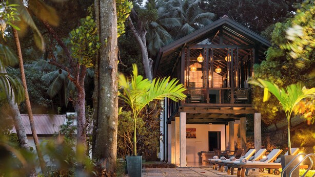 A modern house with a pool, surrounded by lush greenery and palm trees. - Rosyth Estate House (Pinnawala)