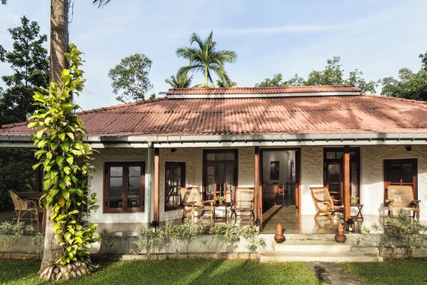 A house with a tiled roof, wooden porch, and outdoor seating. - Rosyth Estate House (Pinnawala)