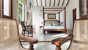 A room with a four-poster bed, wicker chairs, and a view of greenery outside. - Rosyth Estate House (Pinnawala)