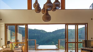A spacious living area with a large sliding glass door leading to a balcony with a mountain view. - Rosyth Estate House (Pinnawala)