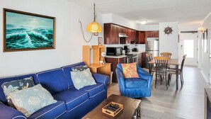 Een moderne woonkamer met een blauwe bank, een salontafel en een eethoek met een houten tafel en stoelen.