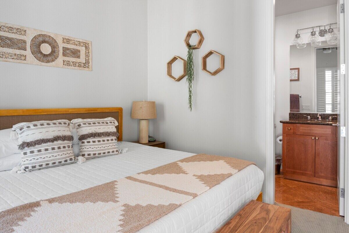 A bedroom with a bed, a nightstand, a lamp, and a wall decoration.