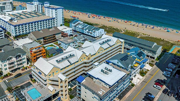 Un hotel sul lungomare con diversi edifici, un parcheggio e una spiaggia sullo sfondo.