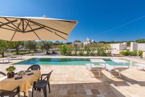 A poolside area with a table and chairs, a covered umbrella, and a view of a building with domed structures.