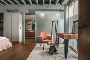 A modern bedroom with a bed, a wooden desk, a chair, and a large mirror.
