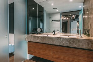 A modern bathroom with a large mirror, two sinks, and a wooden vanity.