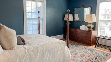 A bedroom with a bed, dresser, mirror, and a patterned rug.