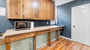 A kitchen with wooden cabinets, a microwave, a sink, and a door. - Leatherwood Loft-Downtown Oasis (Eureka Springs)
