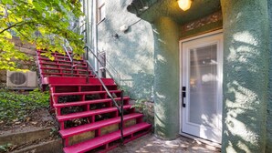 A set of red stairs leading to a door with a textured wall and a small window. - Leatherwood Loft-Downtown Oasis (Eureka Springs)