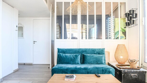 Un salon moderne avec un canapé de couleur turquoise, une table basse en bois et un luminaire suspendu.