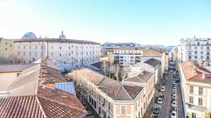 Une vue urbaine comprenant des bâtiments historiques, un dôme imposant et une rue bordée de voitures garées.