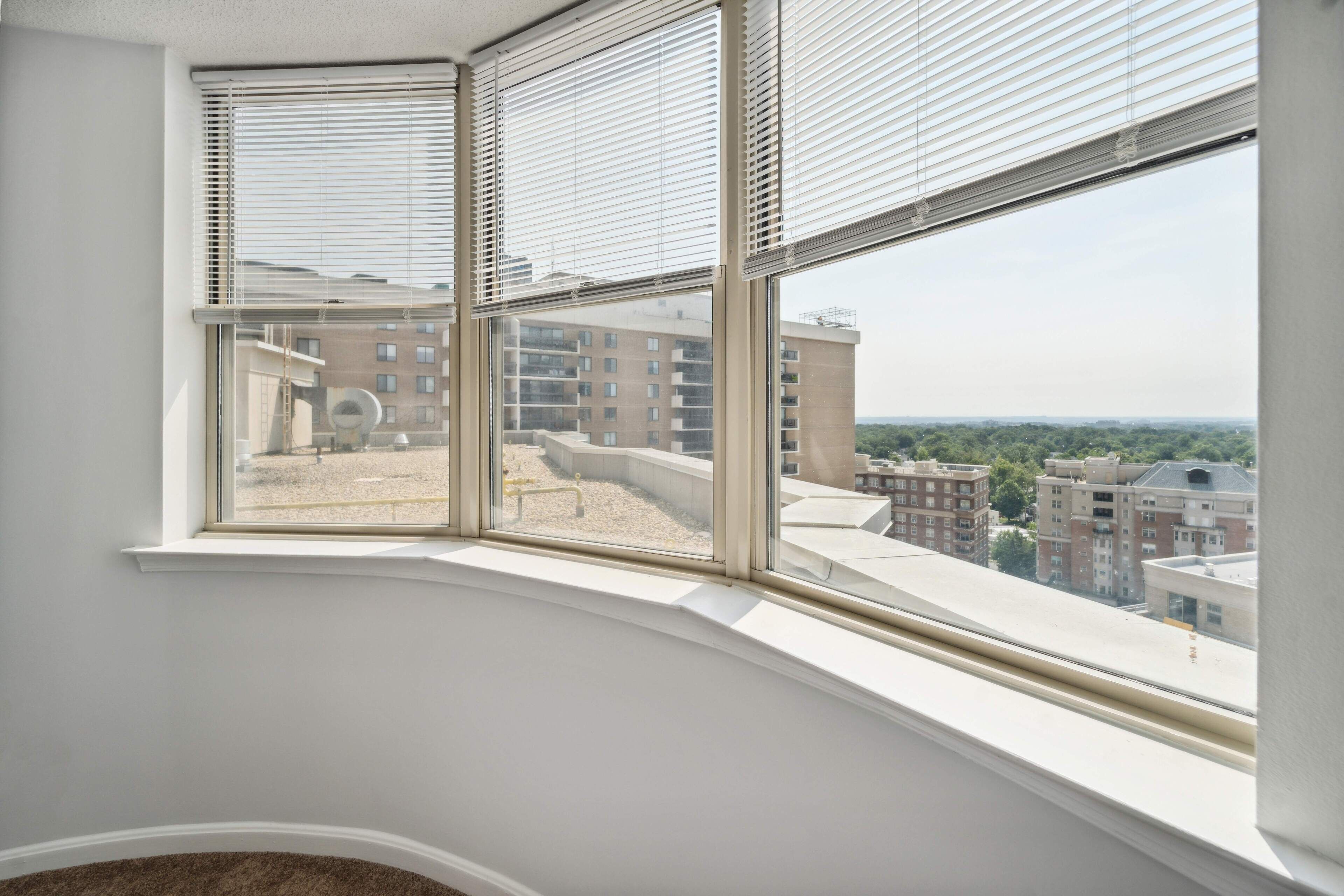 Habitación de esquina con un amplio ventanal con vistas a un paisaje urbano.