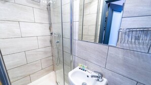 A modern bathroom with a glass-enclosed shower, a white sink, and a small window. - Charming 1-bed Studio in Birmingham (Birmingham)
