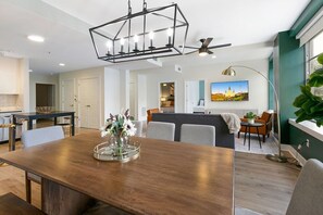 A modern living room with a wooden dining table, grey sofas, and a ceiling fan. - Timeless Elegance: 4BR Luxury Condo in New Orleans (New Orleans)