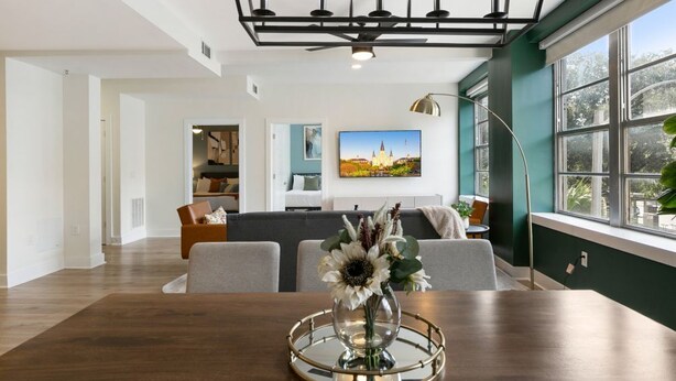 Una sala de estar moderna con una mesa de comedor de madera, un conjunto de sofá y un ventanal con vistas a la vegetación.