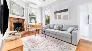 A living room with a fireplace, a sofa, a coffee table, and a chandelier. - Peaceful & Light Paddington home (Paddington)