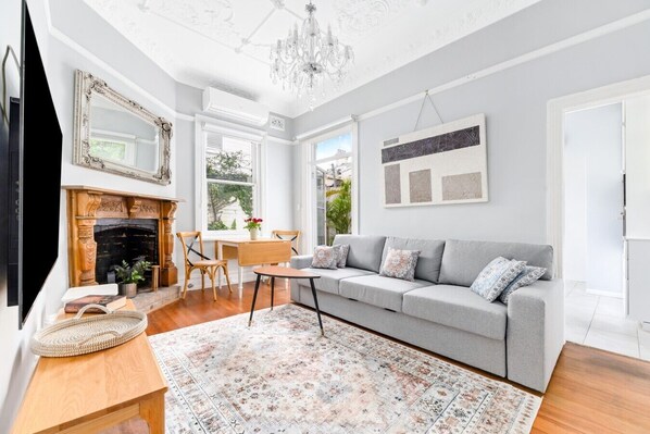 A living room with a fireplace, a sofa, a coffee table, and a chandelier. - Peaceful & Light Paddington home (Paddington)