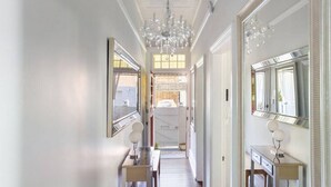 A hallway with chandeliers, a large mirror, and a door leading to a room. - Peaceful & Light Paddington home (Paddington)
