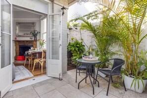 An open door leading to a dining area with a table and chairs, a potted plant, and a view of a brick wall. - Peaceful & Light Paddington home (Paddington)