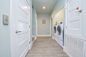 Lavandería con lavadora y secadora, suelo de madera y puertas blancas.