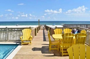 A wooden deck with yellow chairs and tables overlooking a beach. - Lemonshello BeachFront, Hot tub, Heated Pool, 8 bedrooms (Gulf Shores)