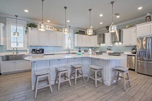 A modern kitchen with white cabinetry, a large island with bar stools, stainless steel appliances, and pendant lighting. - Lemonshello BeachFront, Hot tub, Heated Pool, 8 bedrooms (Gulf Shores)