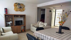 A living room with a sofa, TV stand, and a dining table with chairs. - Cozy Villa in Almoloya de Juárez, Mexico (Almoloya de Juárez)