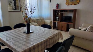A living room with a dining table, sofa, TV stand, and artwork. - Cozy Villa in Almoloya de Juárez, Mexico (Almoloya de Juárez)